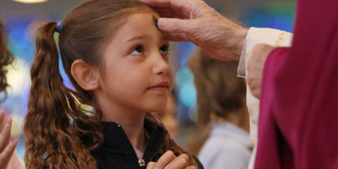 un sacerdote impartiendo la ceniza a una niña.