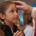 un sacerdote impartiendo la ceniza a una niña.