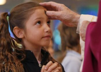 un sacerdote impartiendo la ceniza a una niña.