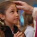 un sacerdote impartiendo la ceniza a una niña.